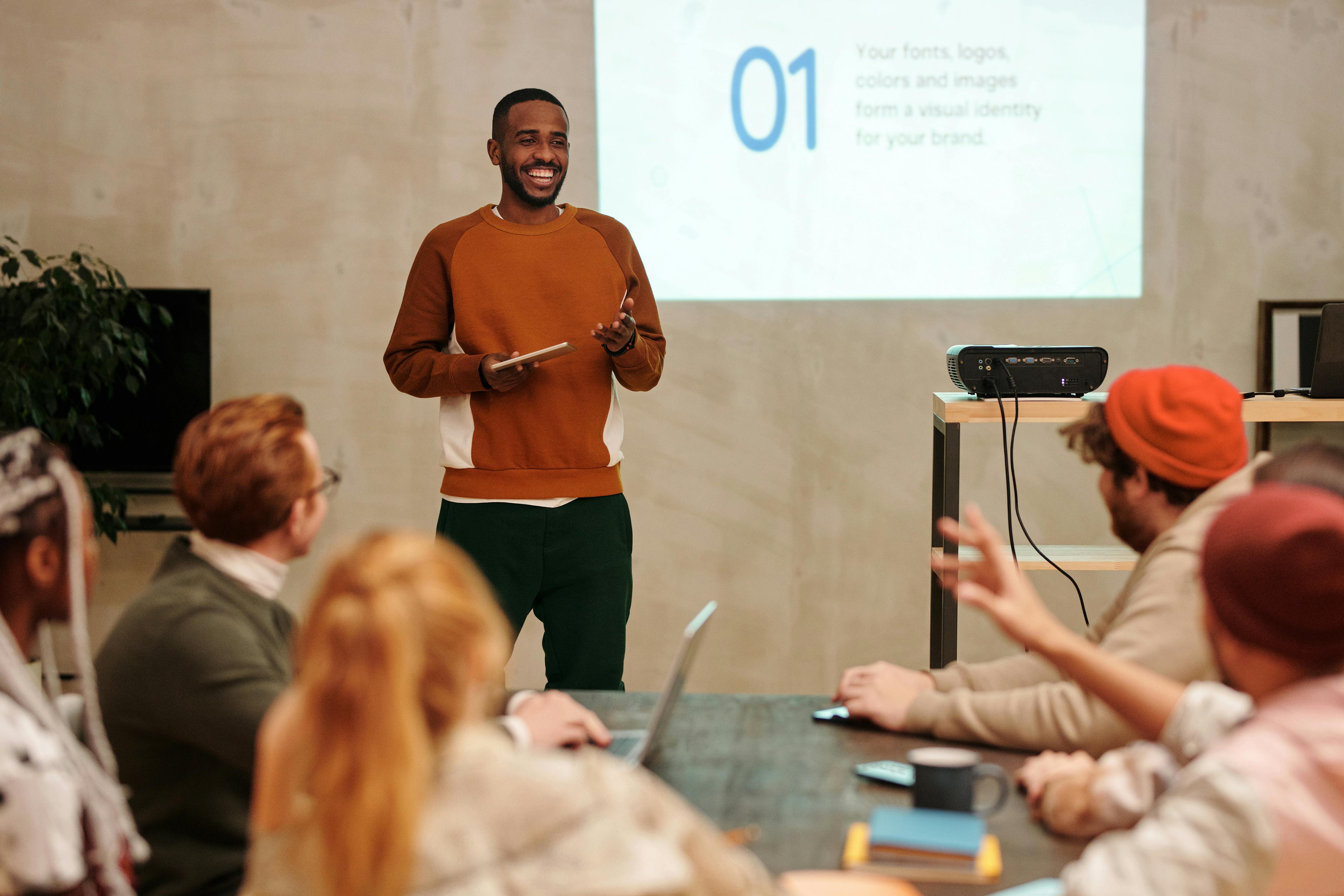 A man delivers a presentation in a modern office to a diverse group of colleagues.